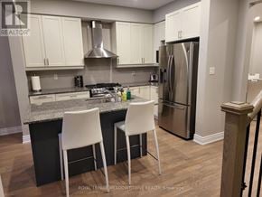 Wasaga Beach townhouse for rent - A kitchen with white chairs and a stainless steel refrigerator.