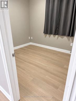 St. Catharines (Carlton/Bunting) duplex for rent - A room with light wood flooring and a grey curtain.