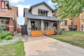 Windsor apartment for rent - A house with a grey roof and a black gate is surrounded by greenery.