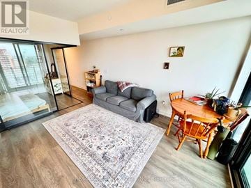 Toronto (Dufferin Grove) condo for rent - A living room with a grey couch and a wooden table.