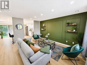 Kitchener multi-family for rent - A living room with a grey sofa and green chairs.