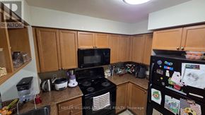 Mississauga (City Centre) condo for rent - A kitchen with a black stove top oven and a black microwave.