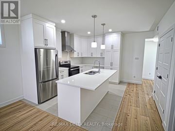 Clarence-Rockland apartment for rent - A modern kitchen with white cabinets and a wooden floor.