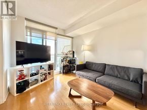 Toronto (Bayview Village) condo for rent - A living room with a grey couch, a wooden coffee table, and a flat screen TV.