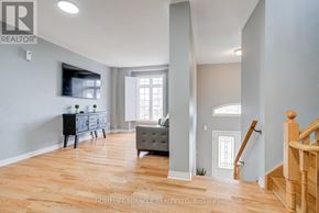 New Tecumseth (Alliston) apartment for rent - A spacious living room with wooden floors and a staircase on the right.