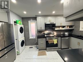 Ajax (South East) apartment for rent - A modern kitchen with stainless steel appliances and black countertops.
