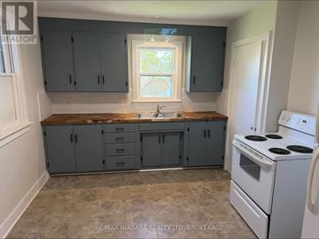 Fort Erie (Central) apartment for rent - A kitchen with a white stove and grey cabinets.