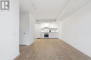 Toronto (Thorncliffe Park) condo for rent - A spacious, empty room with a kitchen area in the background.