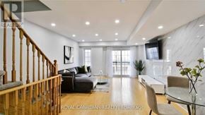 Oshawa (Windfields) townhouse for rent - A spacious living room with a dark sofa and a glass coffee table.