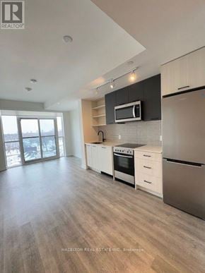 Toronto (Junction Area) condo for rent - A modern kitchen with a refrigerator, oven, and microwave.