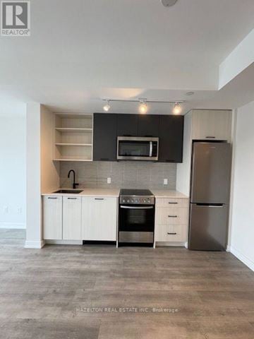 Toronto (Junction Area) condo for rent - A modern kitchen with white cabinets and stainless steel appliances.