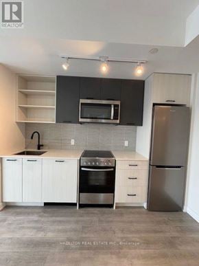 Toronto (Junction Area) condo for rent - A modern kitchen with a stainless steel refrigerator and white cabinets.