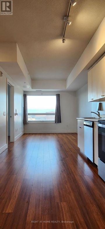 Brantford condo for rent - A kitchen with white cabinets and a wooden floor.