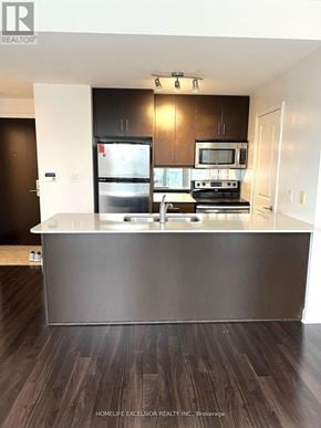 Mississauga (City Centre) condo for rent - A modern kitchen with dark wood floors and stainless steel appliances.