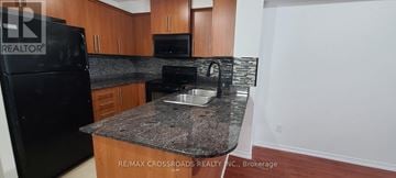 Toronto (Malvern) condo for rent - A kitchen with a black fridge and a granite counter top.