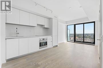 Toronto (Thorncliffe Park) condo for rent - A spacious kitchen with white cabinets and a view of the city.