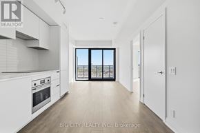 Toronto (Thorncliffe Park) condo for rent - A spacious kitchen with white cabinets and a view of the city through the window.