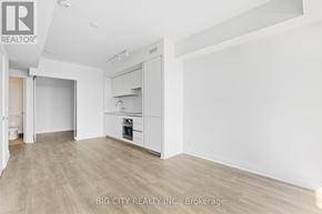 Toronto (Thorncliffe Park) condo for rent - A spacious, empty room with a kitchen area in the background.