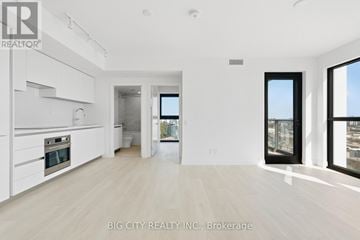 Toronto (Thorncliffe Park) condo for rent - A spacious, well-lit kitchen with white cabinets and a large window.
