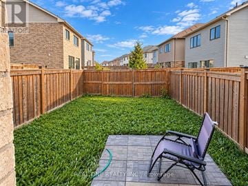 Haldimand townhouse for rent - A backyard with a wooden fence and a chair.