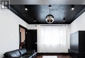 St. Catharines (Old Glenridge) apartment for rent - A black leather sofa sits in a room with a black ceiling and a chandelier hanging from it.