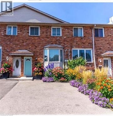 Hamilton townhouse for rent - A house with a blue door and windows surrounded by a flower garden.