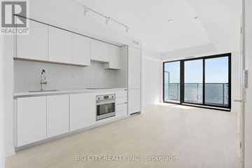 Toronto (Thorncliffe Park) condo for rent - A modern kitchen with white cabinets and a large window.
