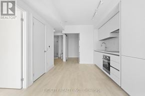 Toronto (Thorncliffe Park) condo for rent - A white kitchen with wooden floors and white cabinets.