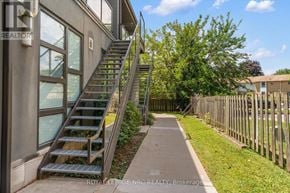 St. Catharines (Lakeport) multi-family for rent - A metal staircase with a handrail is on the left side of a concrete path.