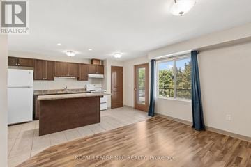 St. Catharines (Lakeport) multi-family for rent - A kitchen with brown cabinets and a white fridge is shown.