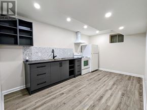 Newmarket (Huron Heights-Leslie Valley) apartment for rent - A kitchen with a white refrigerator, black cabinets, and a wooden floor.