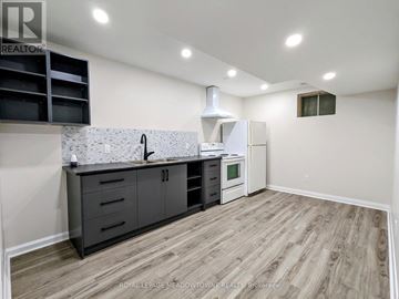Newmarket (Huron Heights-Leslie Valley) apartment for rent - A kitchen with a white refrigerator, black cabinets, and a wooden floor.