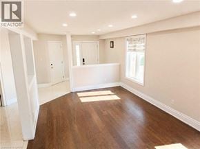 Kitchener apartment for rent - A spacious room with wooden flooring and white walls.