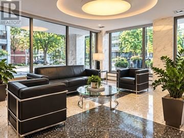 Toronto (Annex) condo for rent - A living room with a black couch and a glass table.