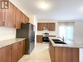 Georgina (Sutton & Jackson's Point) apartment for rent - A kitchen with wooden cabinets and a black refrigerator.