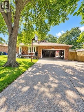 Tecumseh apartment for rent - A house with a garage and a tree in front.