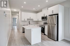 Azilda apartment for rent - A modern kitchen with white cabinets and stainless steel appliances.