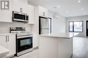 Azilda apartment for rent - A modern kitchen with white cabinets and stainless steel appliances.