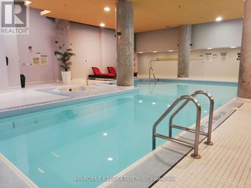 Toronto (Bay Street Corridor) condo for rent - A swimming pool inside a building with a red couch and a plant.