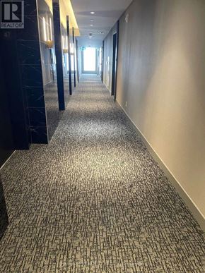 Vaughan (Vaughan Corporate Centre) condo for rent - A hallway with a carpeted floor and a sign that says "REALTOR" on the wall.