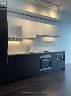 Vaughan (Vaughan Corporate Centre) condo for rent - A modern kitchen with dark wood cabinets and stainless steel appliances.