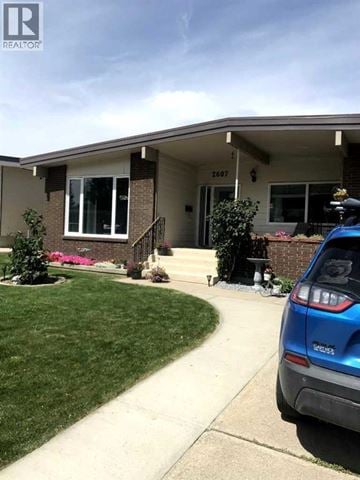 Lethbridge apartment for rent - A blue car is parked in front of a house with the number 2607 on it.