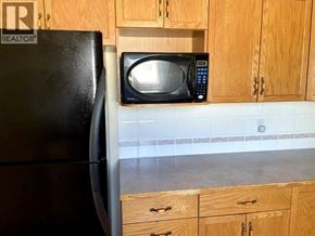 Lethbridge apartment for rent - A black refrigerator is in a kitchen with wooden cabinets.