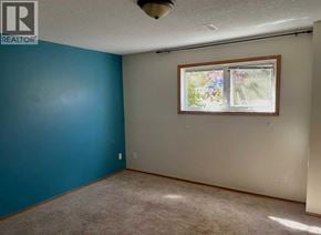 Lethbridge apartment for rent - A room with a blue wall and a window with a view of trees and flowers.