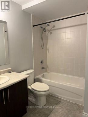 Brampton (Westgate) townhouse for rent - A white toilet sits next to a white bathtub in a bathroom.