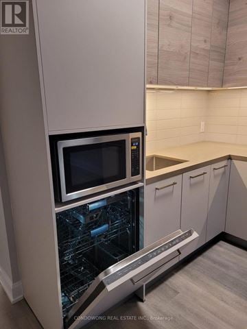 Markham (Commerce Valley) condo for rent - A modern kitchen with a dishwasher and a microwave.