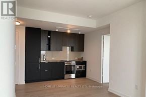 Mississauga (City Centre) condo for rent - A modern kitchen with black cabinets and stainless steel appliances.