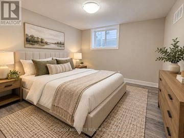 Ottawa fourplex for rent - A bedroom with a large bed, a nightstand with a lamp, and a painting on the wall.