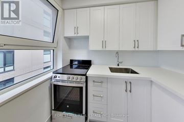 Toronto (Yonge-St. Clair) multi-family for rent - A modern kitchen with white cabinets and a stove top oven.