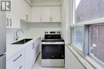Toronto (Yonge-St. Clair) multi-family for rent - A kitchen with white cabinets and a black stove top oven.